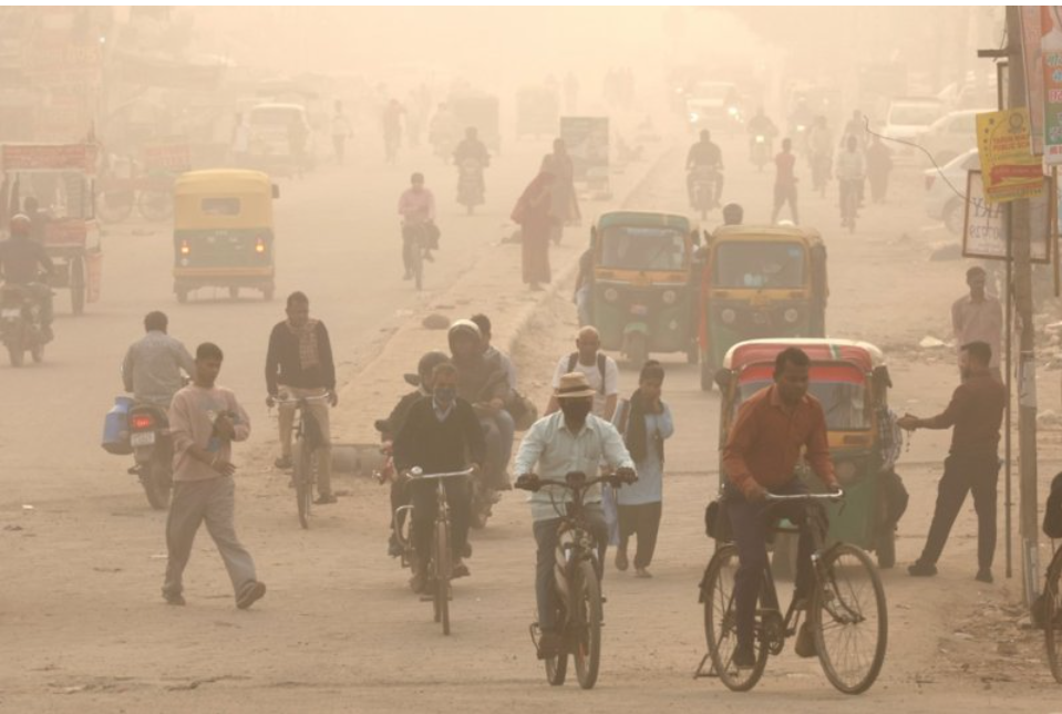 “People commuting on a dusty road in Delhi amid heavy smog and low visibility, highlighting the severe impact of Delhi pollution on daily life and air quality.” Delhi Pollution